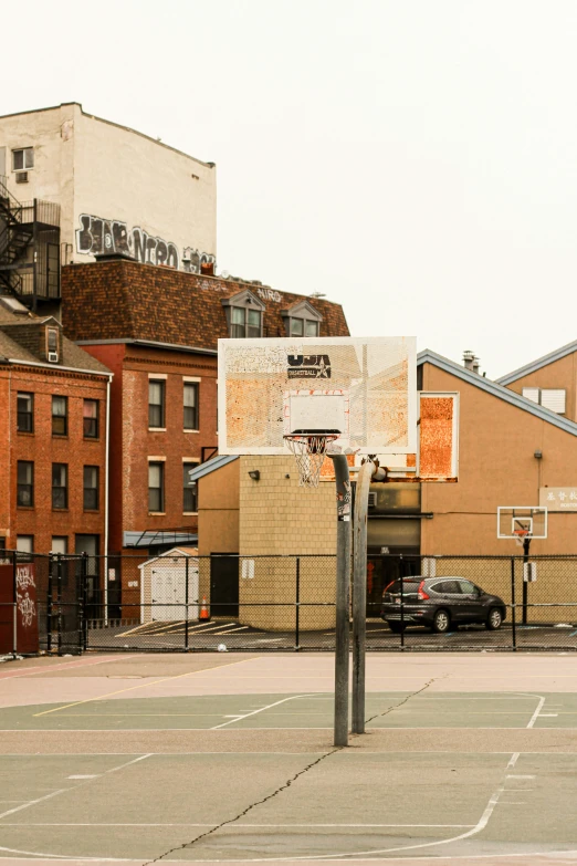 a small basketball court in front of brick buildings