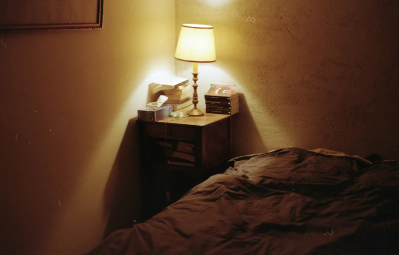 the lamp is on beside a bed with a black comforter