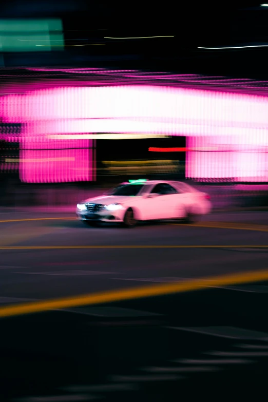 a pink car speeding down the road in the city