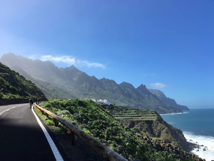 a scenic road leads down the side of a mountain with a lake and a small house on it