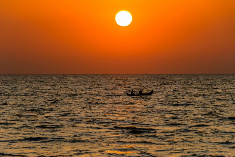 two people in a small boat on the ocean at sunset