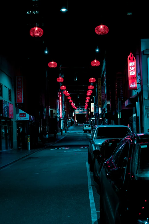 this dark street is lit up with red umbrellas