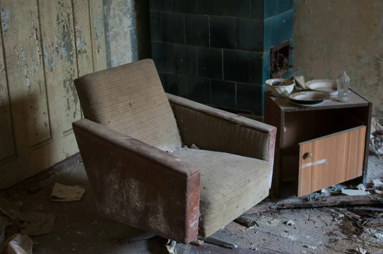 a dirty chair in an empty room next to an old dresser