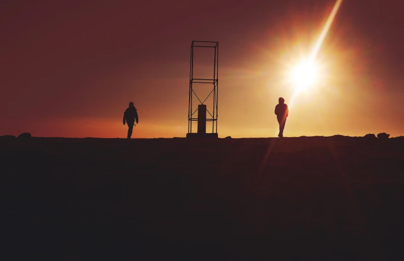 two men stand with their backs towards the sun