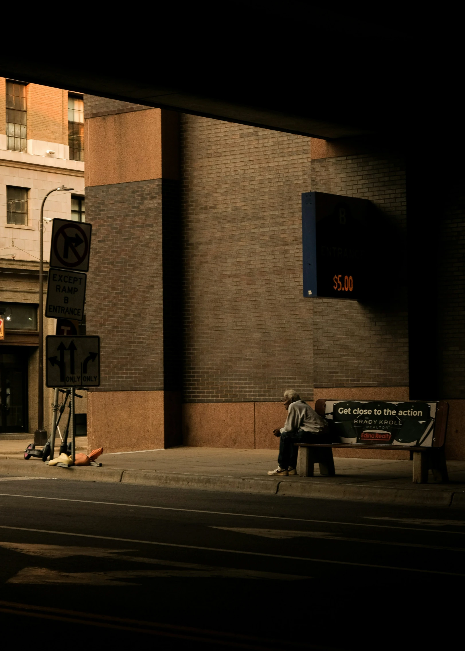 a man is sitting on a bench on a street