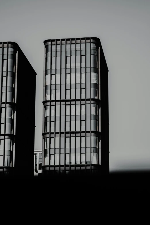 the silhouette of two buildings are shown against a cloudy sky