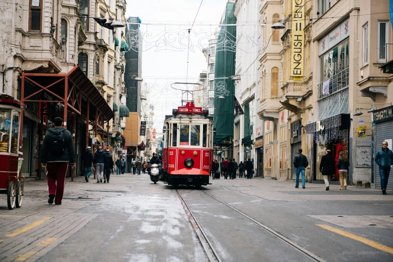 a red trolly car traveling down a street in a town