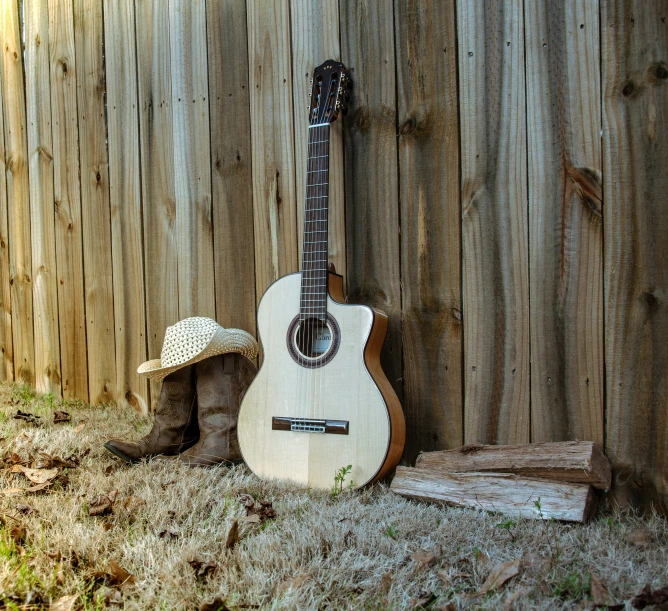 a guitar next to a straw hat on the ground