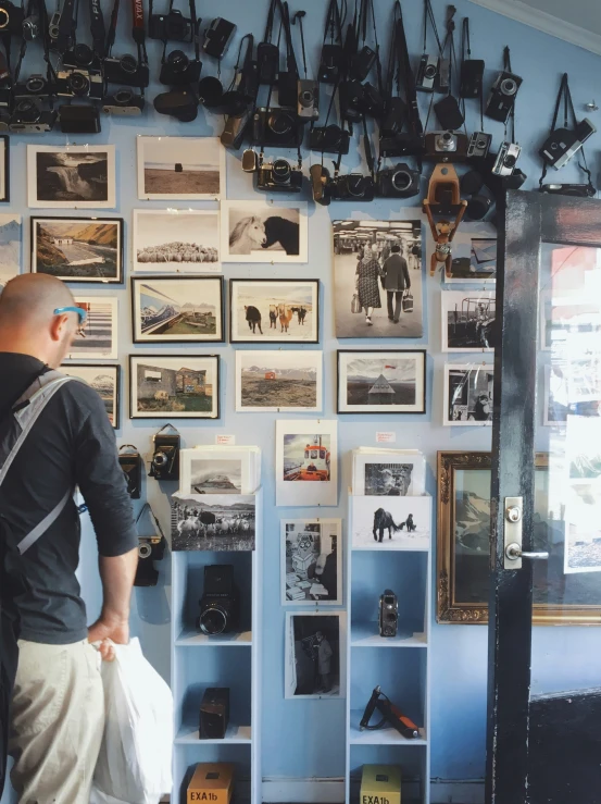 the back of a man looking at pictures on a wall