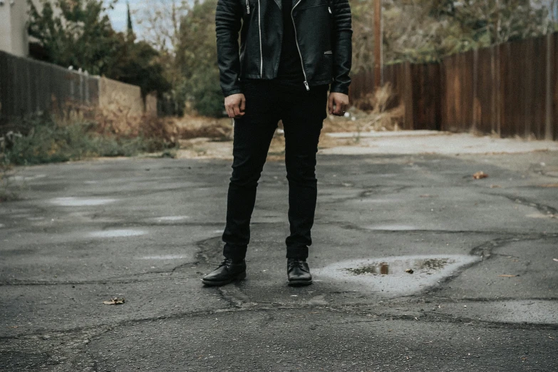 young man in leather jacket standing on empty parking lot