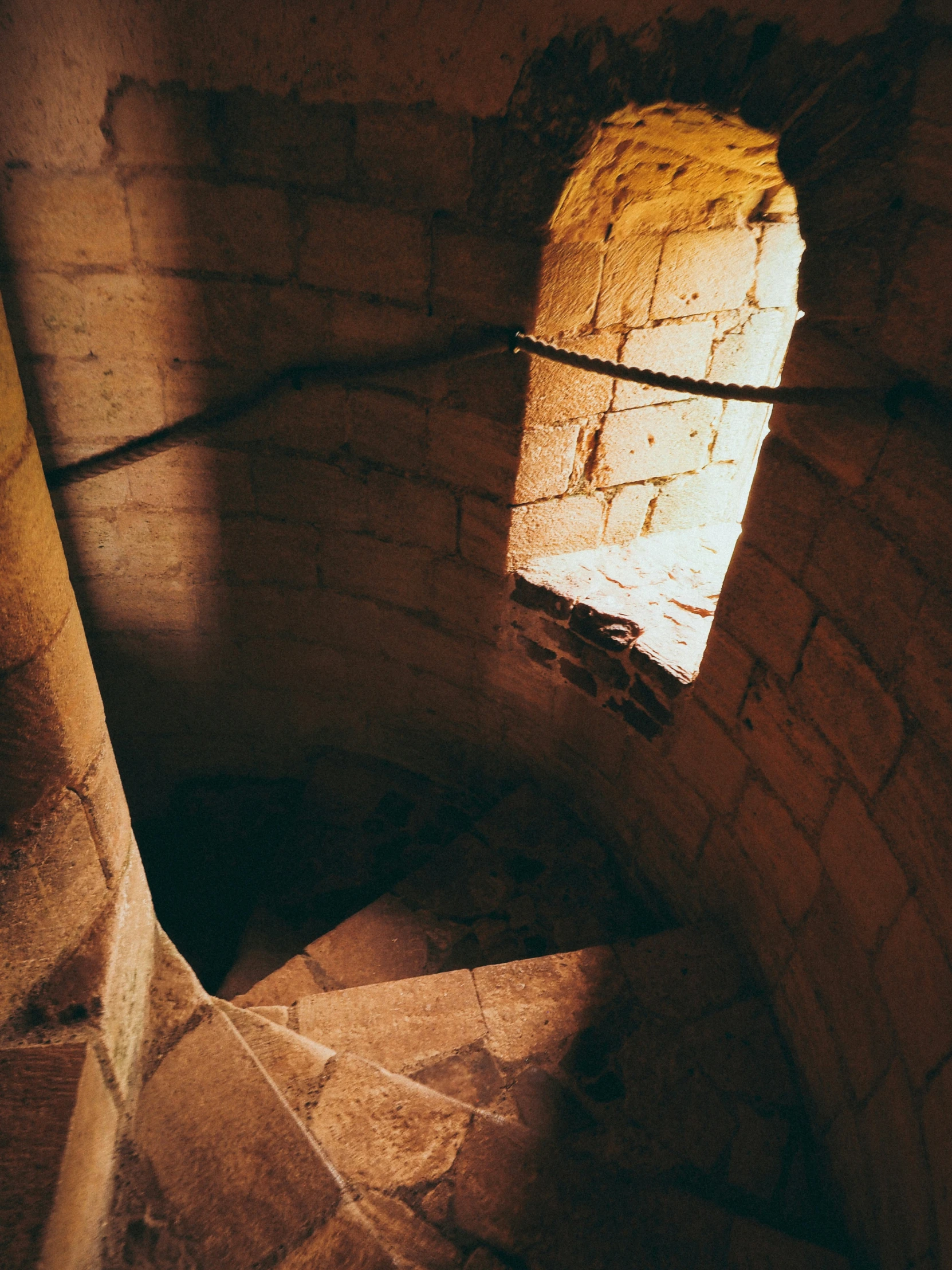 sunlight coming through a window on a stone wall