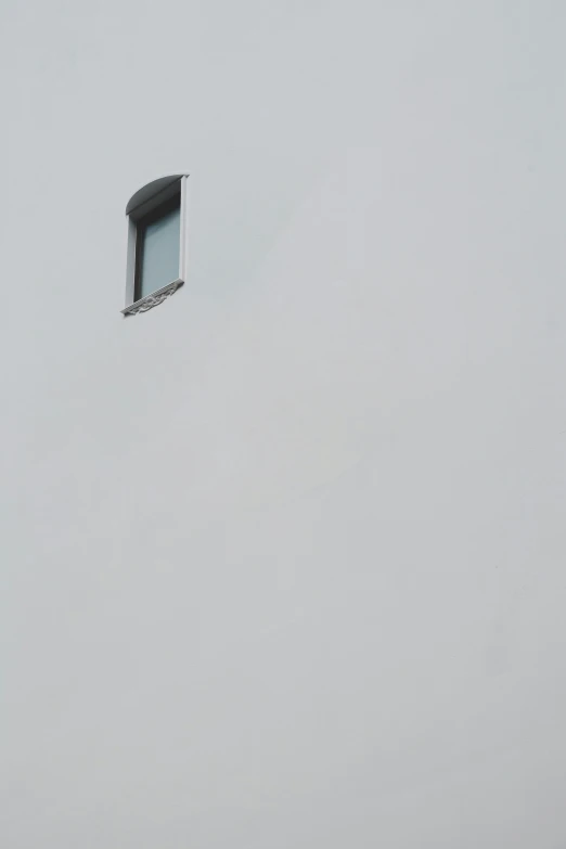 the view from below of a grey, cloudy sky with a window