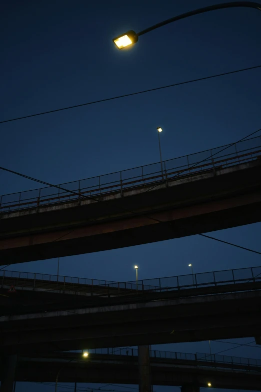 two lights illuminate the silhouette of the light over a bridge at night