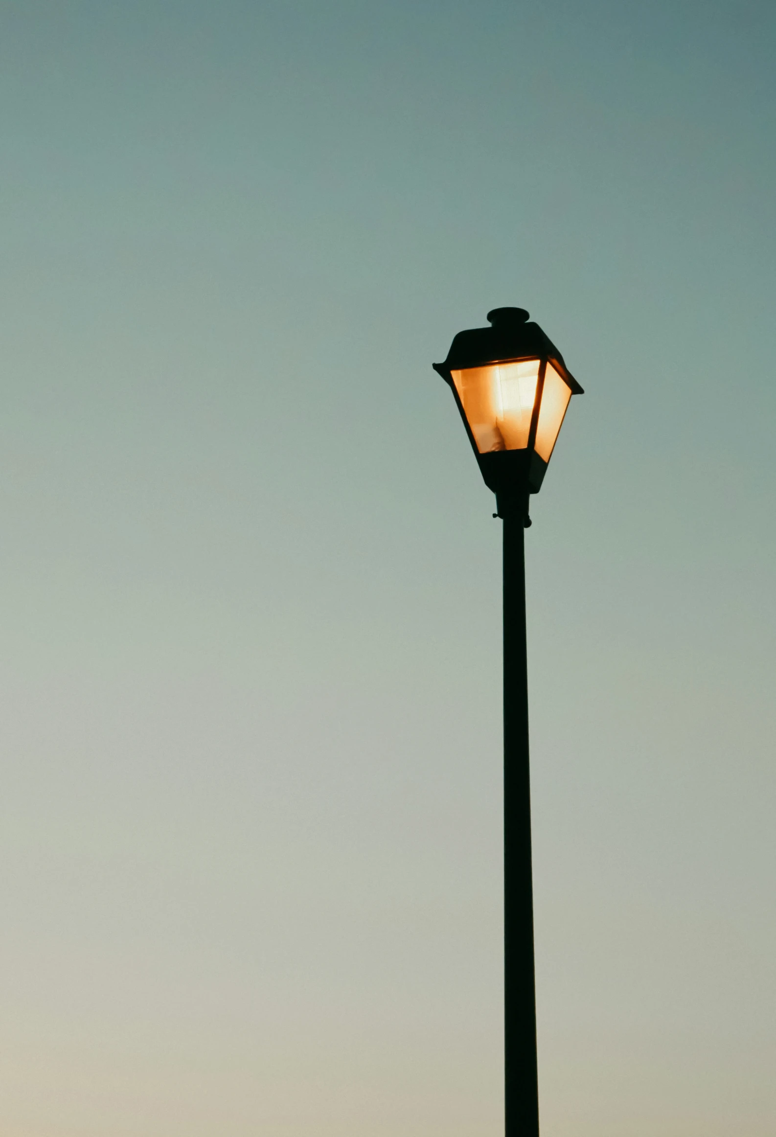 a lamp post is lit up in the evening