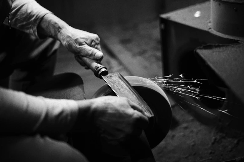 a man holding a big knife while working on soing