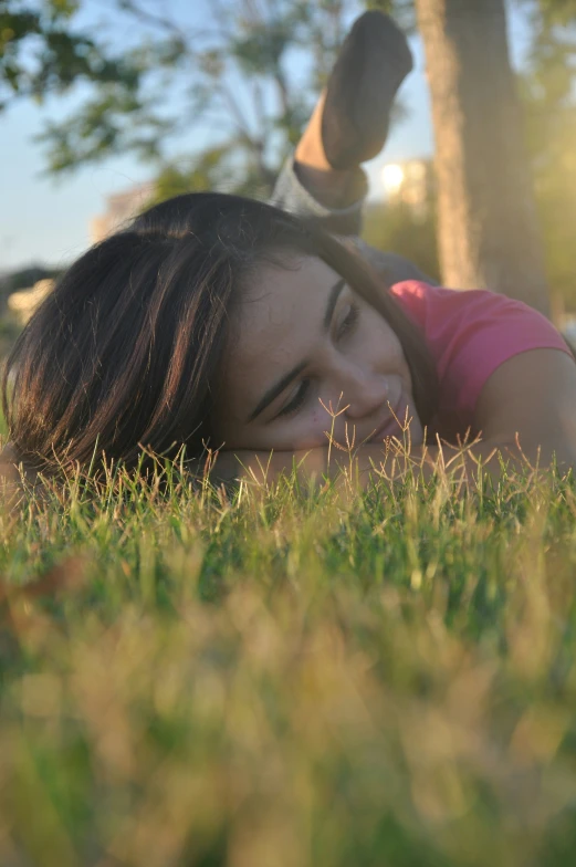 a woman laying in grass with her head against her face