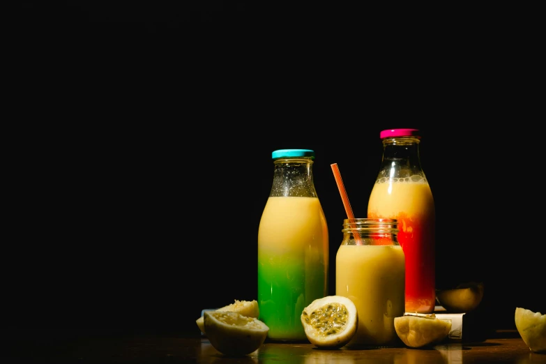 a table with different colored smoothies next to some lemon slices