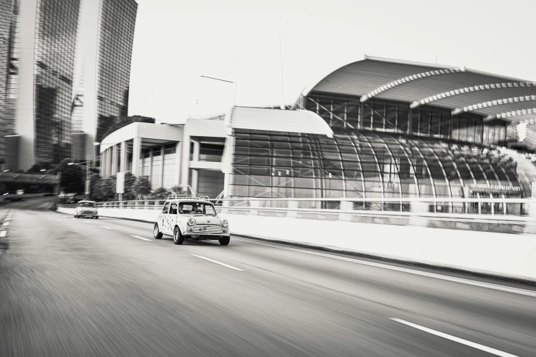 a black and white po of a vehicle driving by a huge building