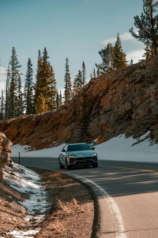 a car driving down a winding road surrounded by snow