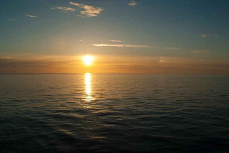 a large body of water with the sun in the distance