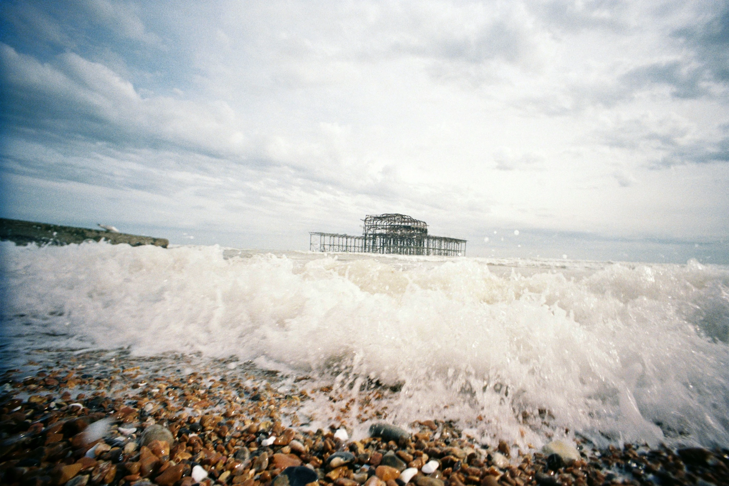 waves crash against a pier as it sits on rocks