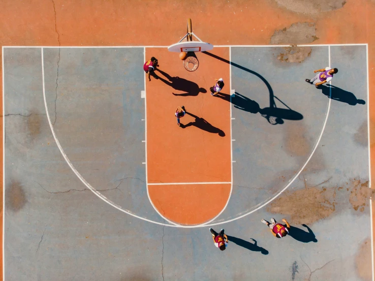 an overhead view of people standing on an orange basketball court