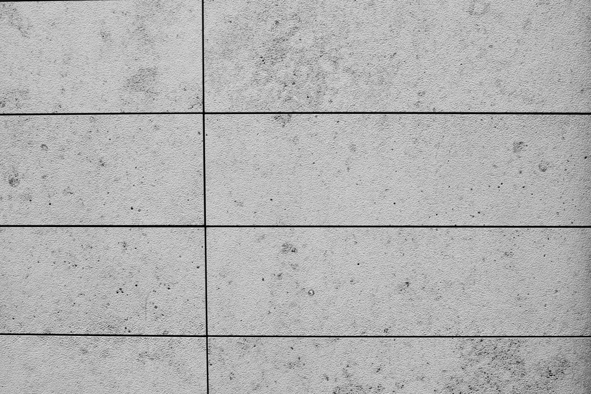 a man walks down a path in front of an empty cement wall