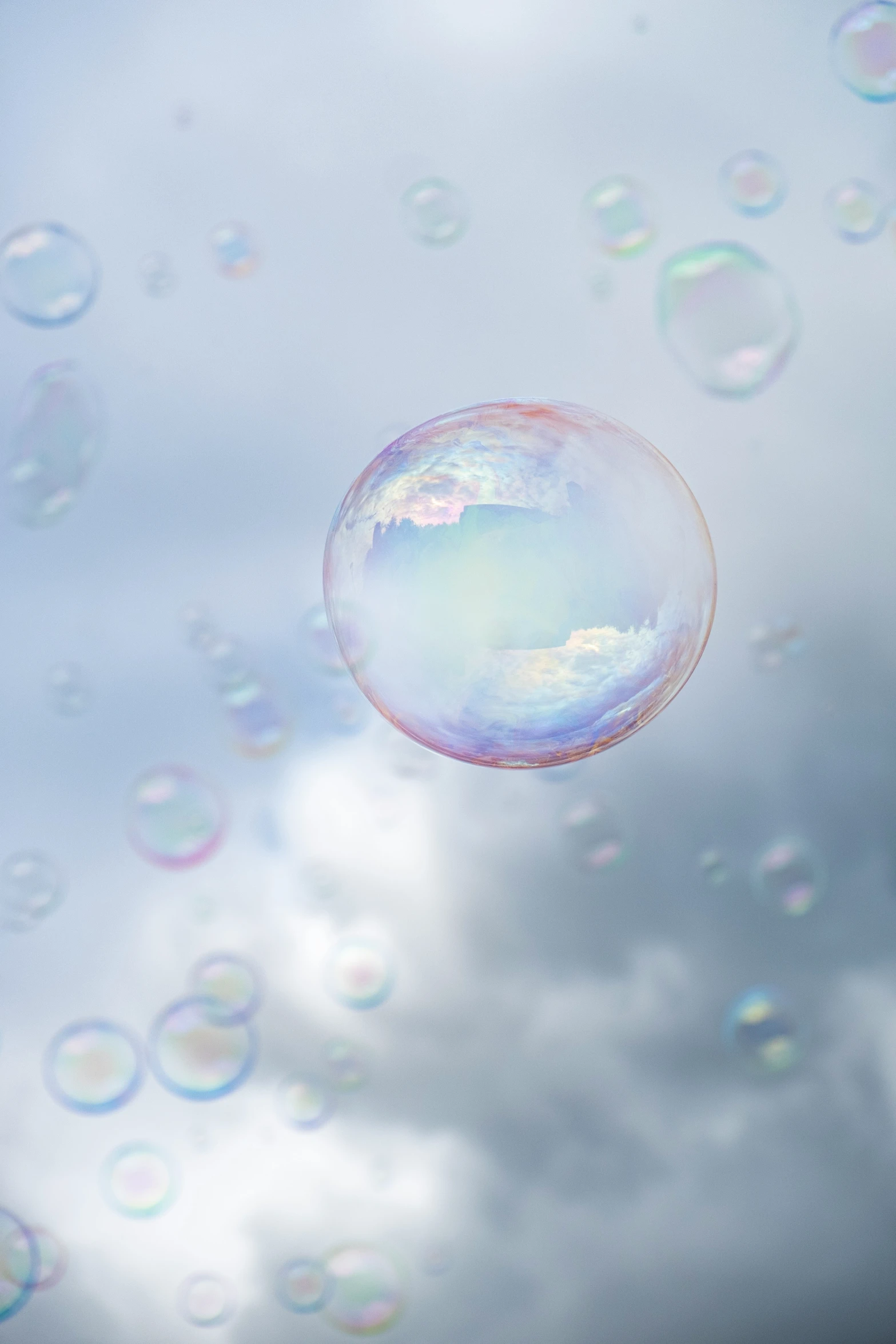 a bubble floats in the sky with a rainbow behind it