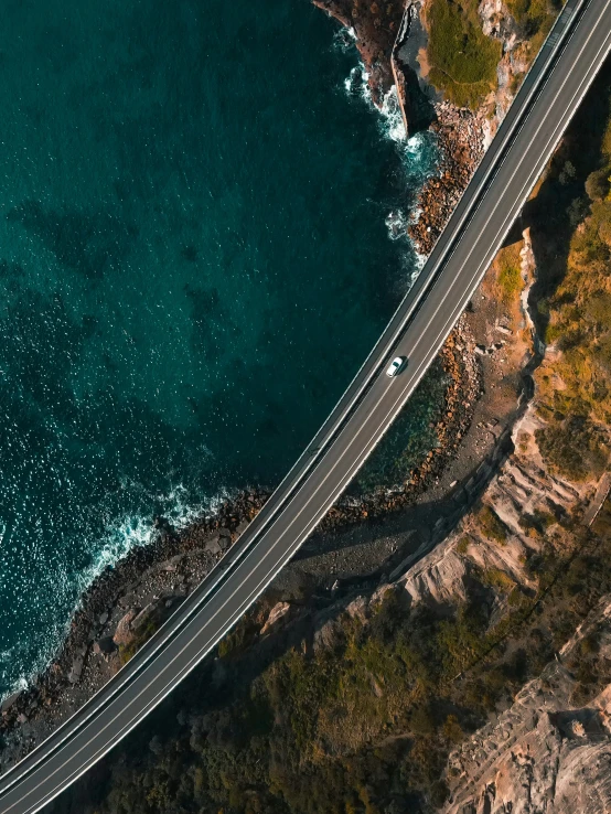 an aerial view of an ocean highway with cars on it