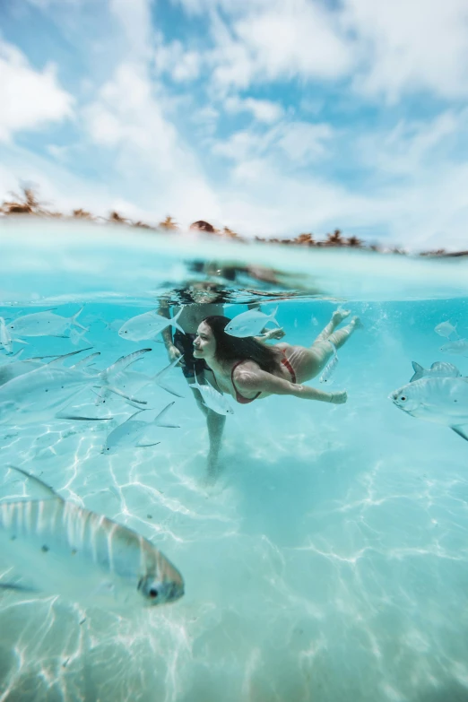 a woman swimming in the water next to fish