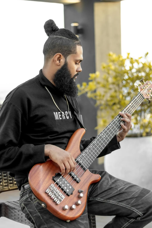 a man with a top knot plays an electric guitar