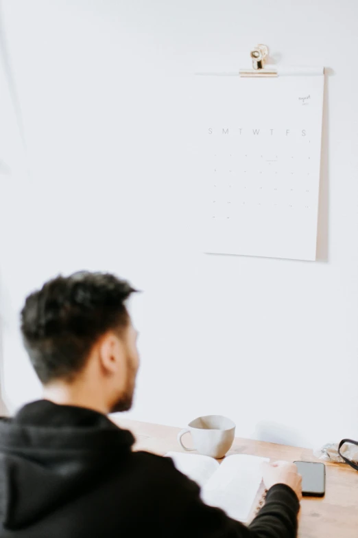 a man sitting at a table with a paper and laptop