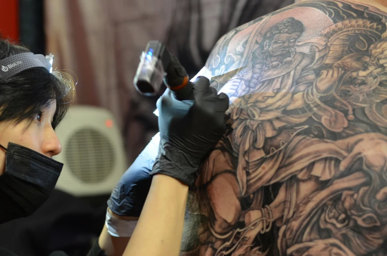 a woman is getting her arm tattooed at a tattoo convention