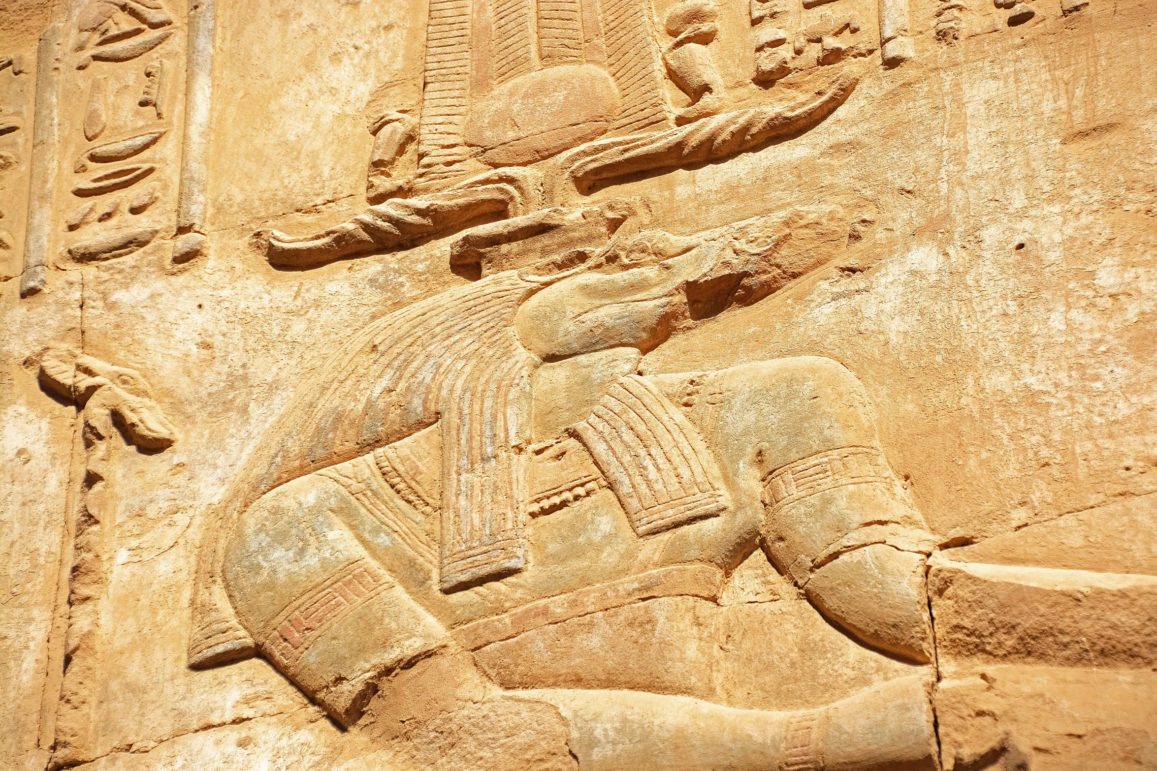 this ancient stone wall is depicting an egyptian god, with another person at the foot of it