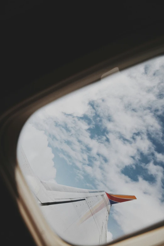 an airplane window shows the wing and blue sky