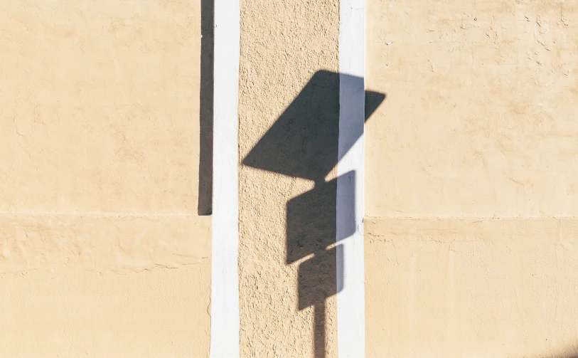 a street sign casting a shadow on a wall