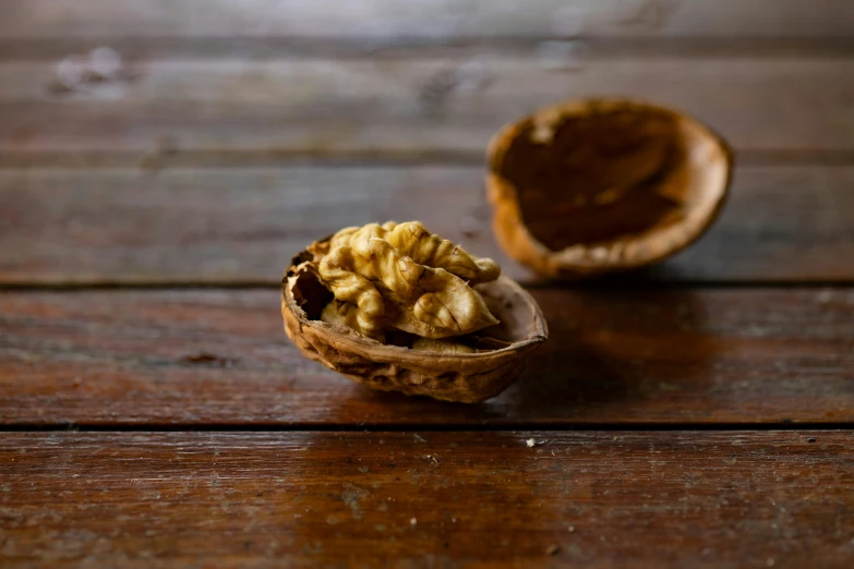 walnuts sitting inside of a shell on wooden surface