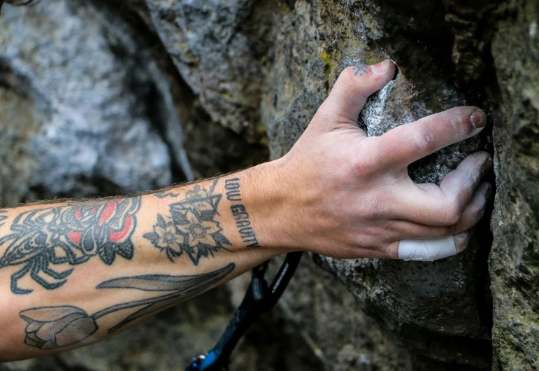 someone with their arm tattoo holding onto a rock face