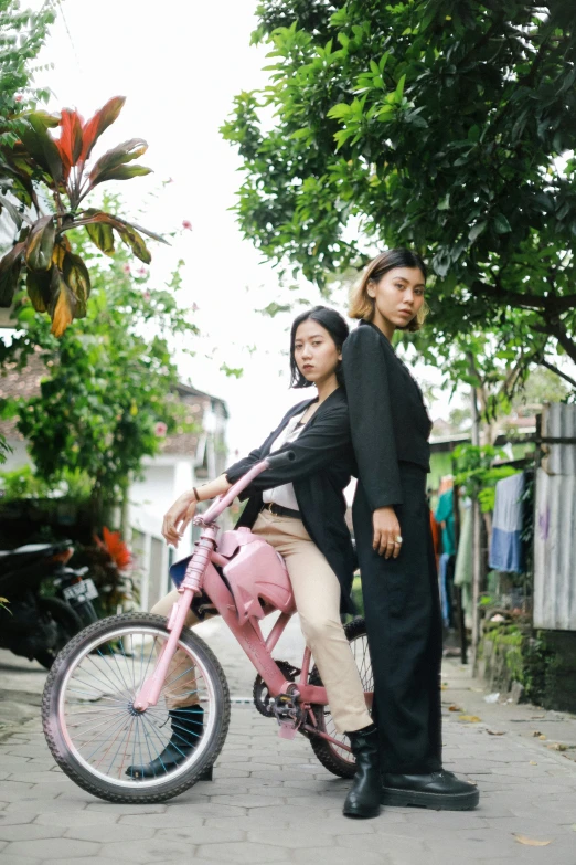 man and woman riding pink bicycle together on street