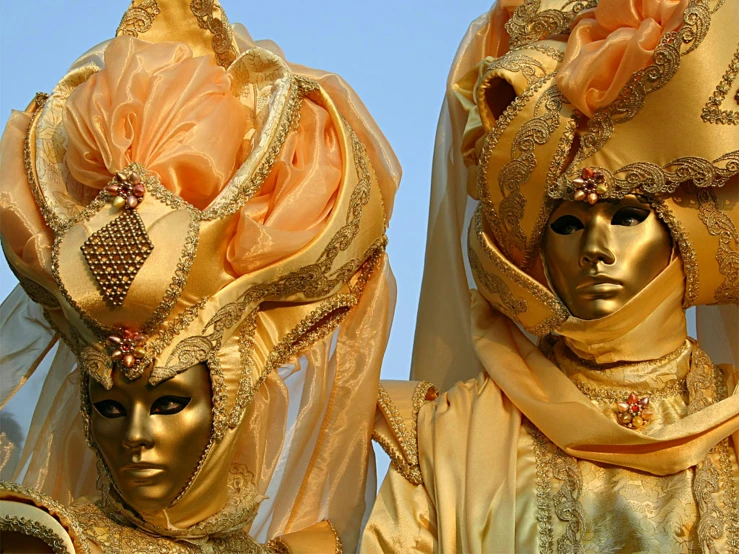 two elaborate golden masks on display under a blue sky