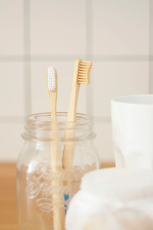 two bamboo toothbrushes inside a jar sitting on a table