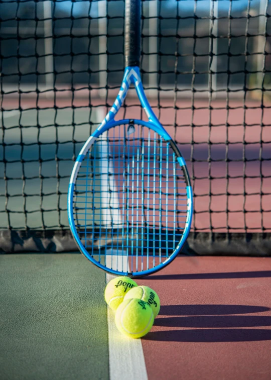 there is a tennis racket and two tennis balls on the ground