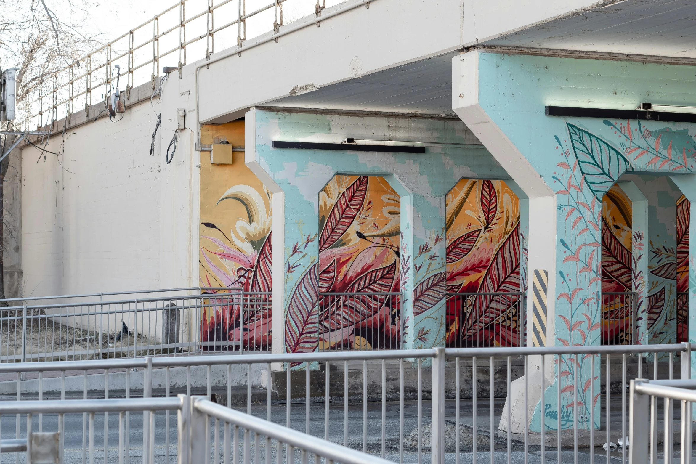 three multi - colored murals in a concrete wall behind a white fence