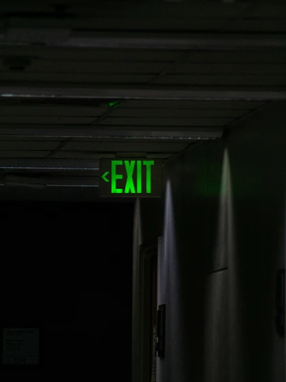a dark room with a neon exit sign