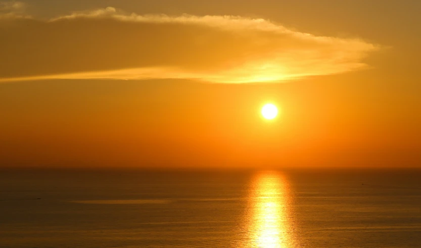 an orange sunset shining over the water of a bay