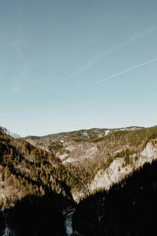 an airplane flying over a large hill surrounded by trees