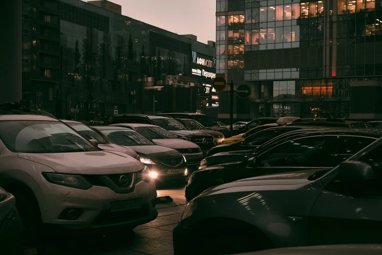 several vehicles are parked near a street in front of some tall buildings