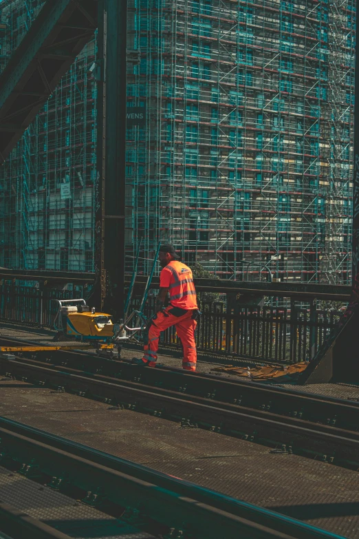 a man wearing an orange uniform on some train tracks