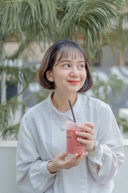 the woman is smiling holding a cup with a straw