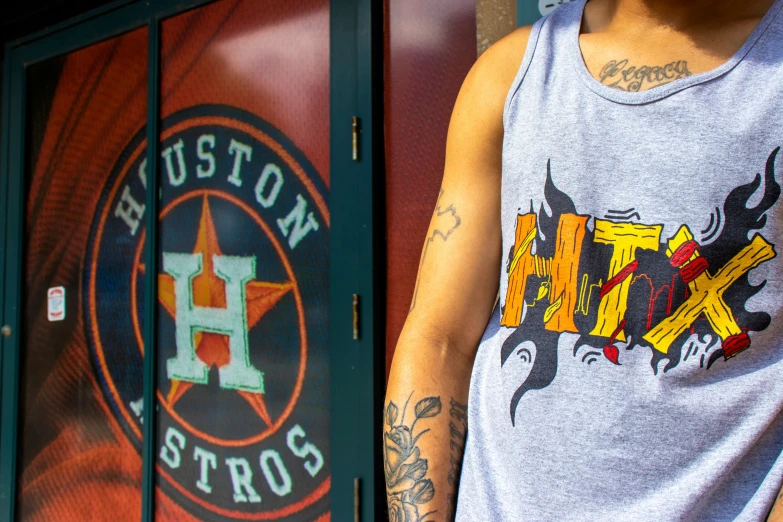 a man with tattoos wearing an houston astros tank top